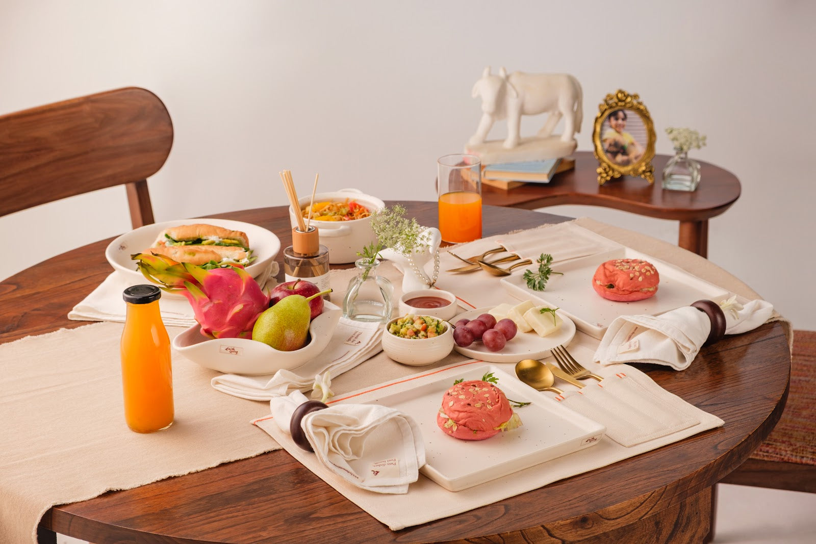 A handcrafted BTEL ceramic table setting with fruit, drinks and linen napkins, set for a home gathering