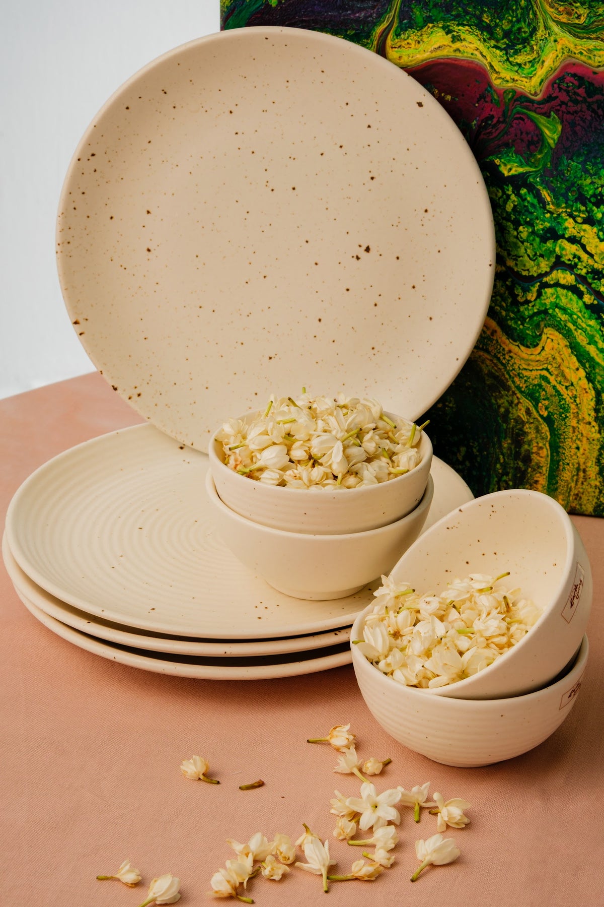 A stacked set of handcrafted cream speckled ceramic plates and bowls, styled as a gift