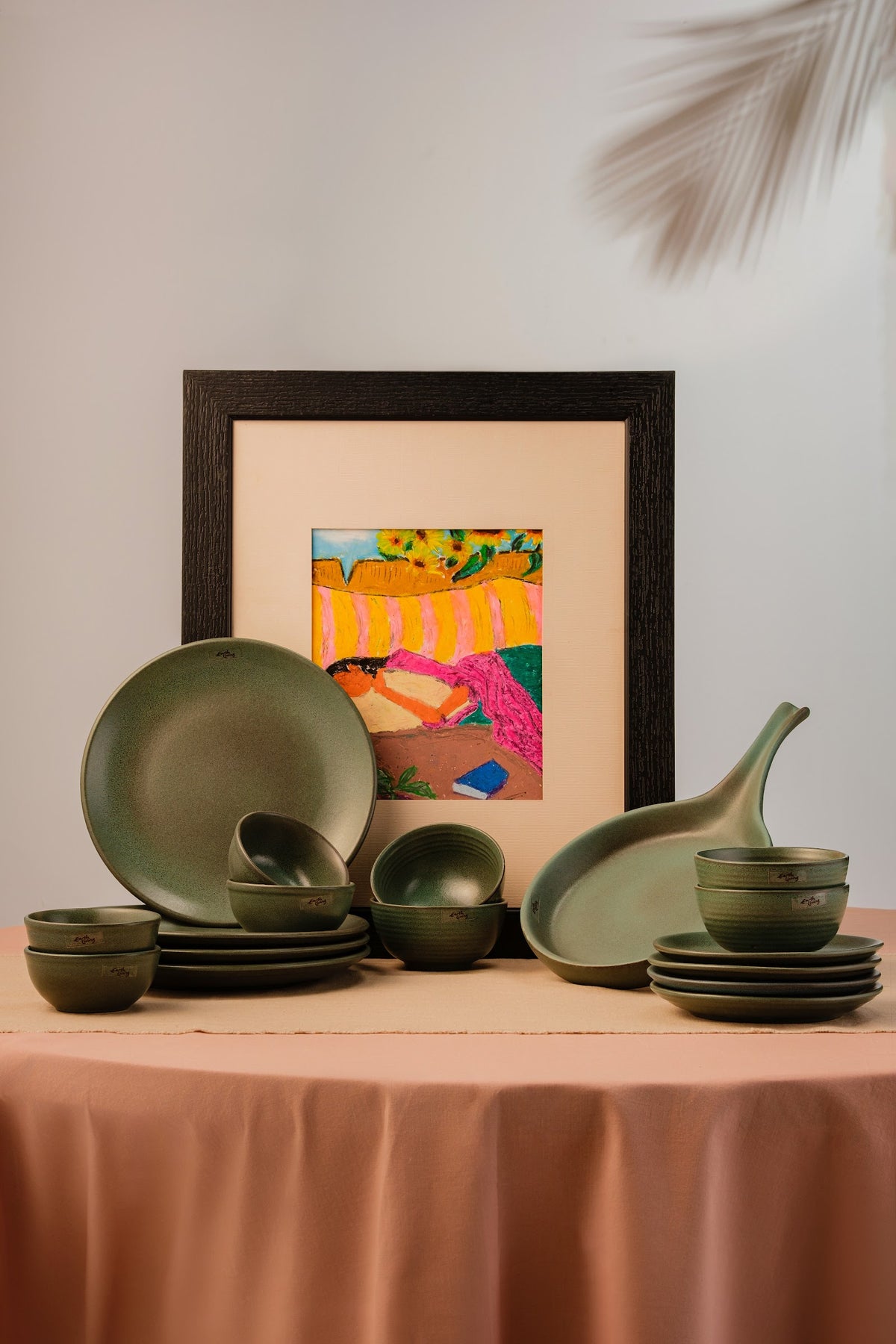 A mixed collection of handcrafted green ceramic plates and bowls stacked together
